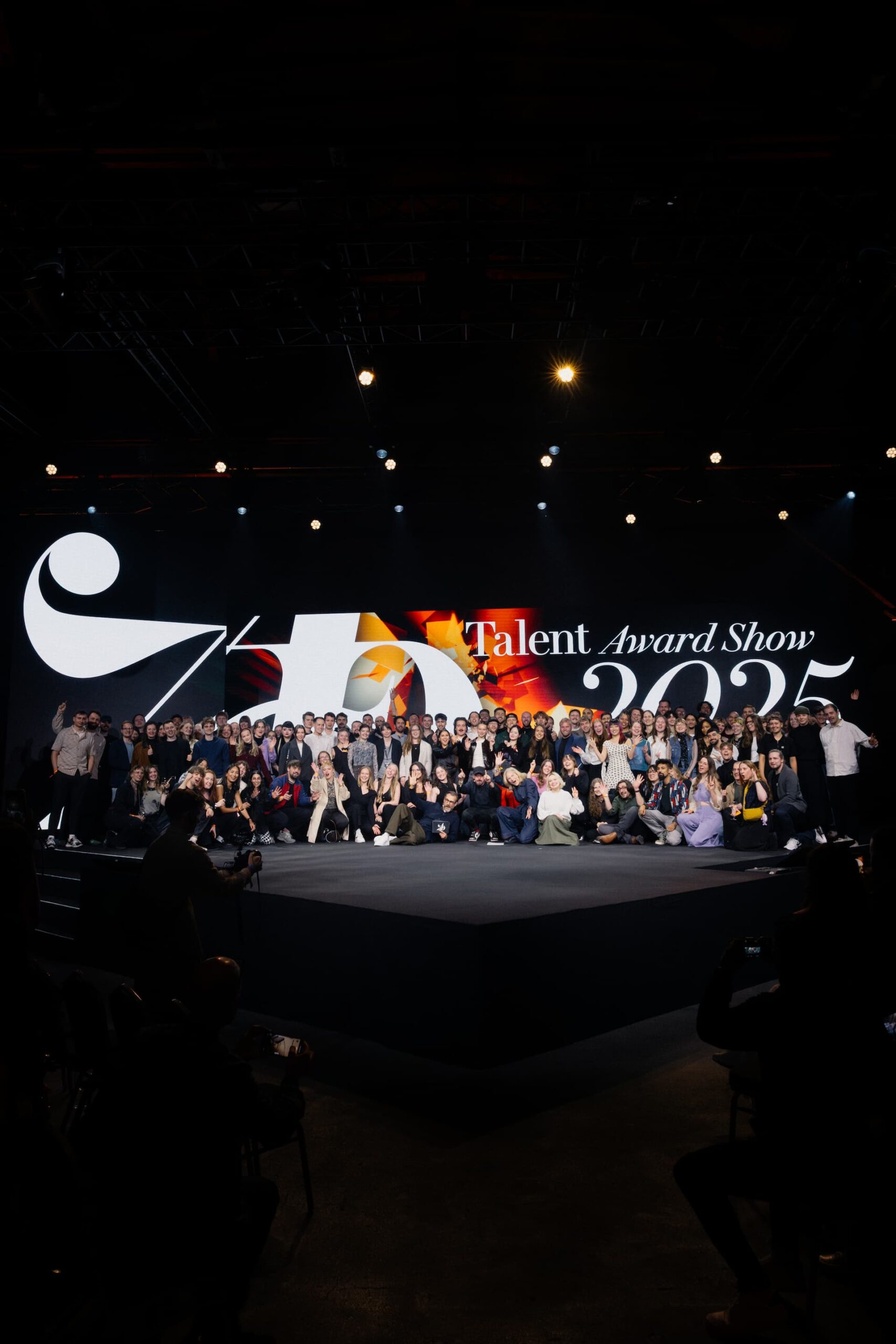 Gruppenaufnahme von allen Gewinnern und Beteiligten des ADC Awards 2025 auf einer großen Bühne, wobei die Jurymitglieder vorne stehen.