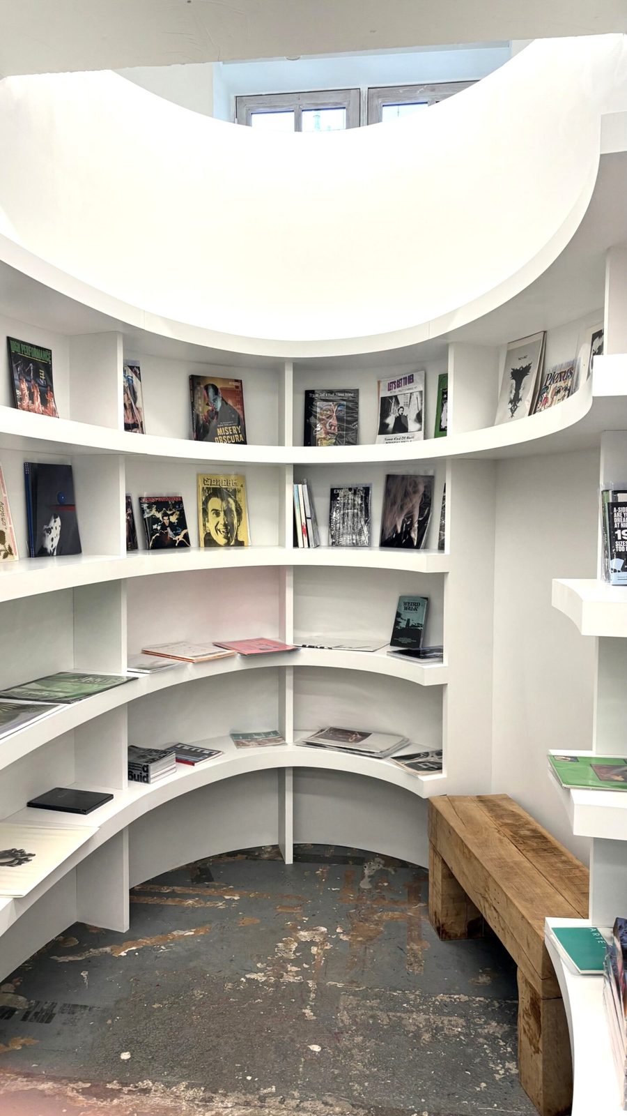 Innenansicht einer modernen Bibliothek mit weißen kurvenförmige Bücherregale mit verschiedenen Zeitschriften und Büchern