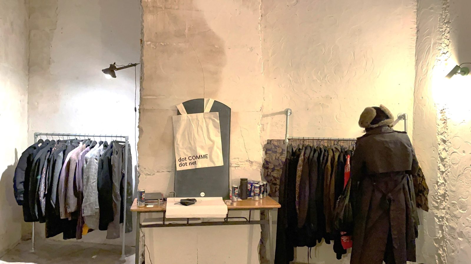 Minimalistisches Innendesign eines Modegeschäfts, mit weißen loftartigen Wänden, mit Kleidungsstücken und Beleuchtung.