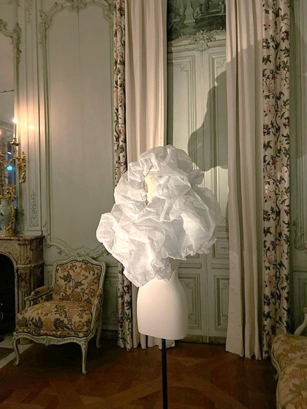 Weißes Avantgarde-Modestück auf einem Mannequin vor einem historischen Hintergrund in einem opulenten Raum mit antiken Möbeln