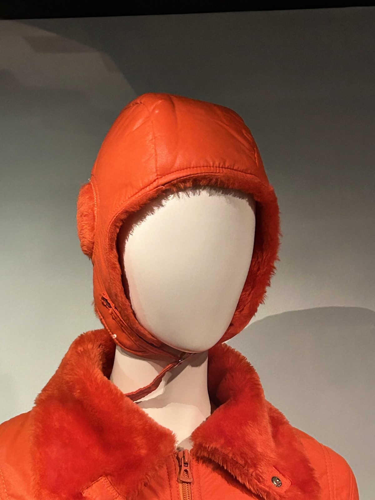 Schaufensterpuppe mit futuristischer, orangefarbener Mütze und Jacke