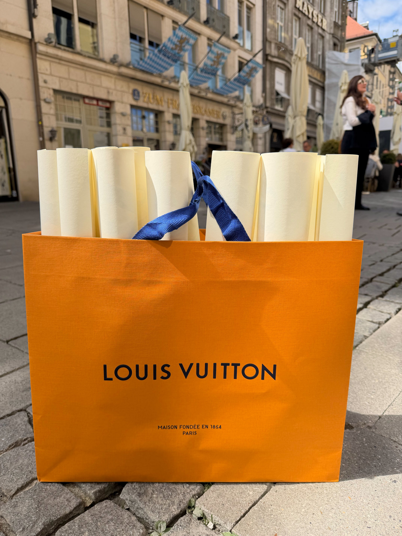 Louis‑Vuitton‑Tasche mit eingerollten Papieren auf einer Münchner Straße
