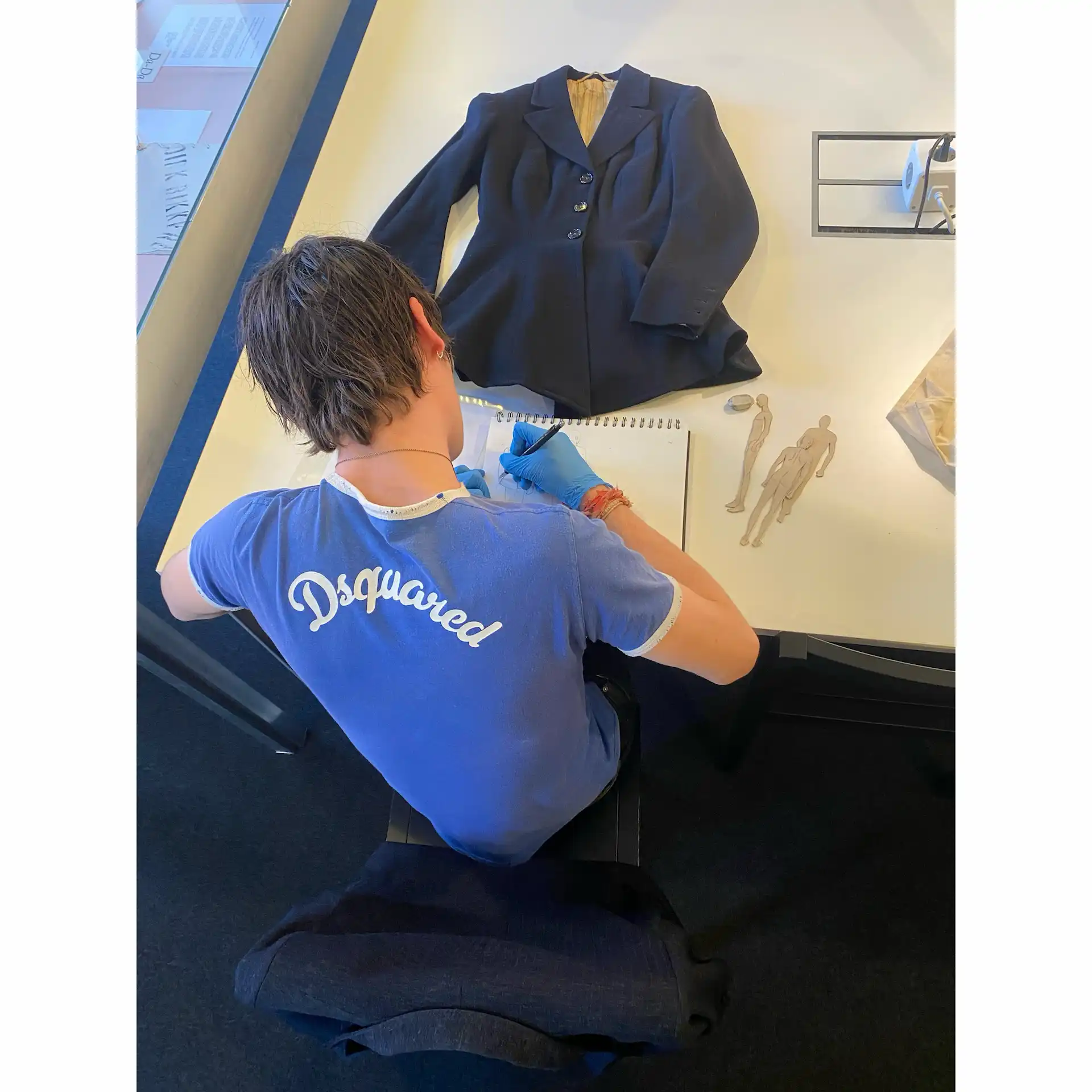 Modedesign-Student analysiert einen schwarzen Blazer und fertigt Skizzen im MoMu Antwerpen