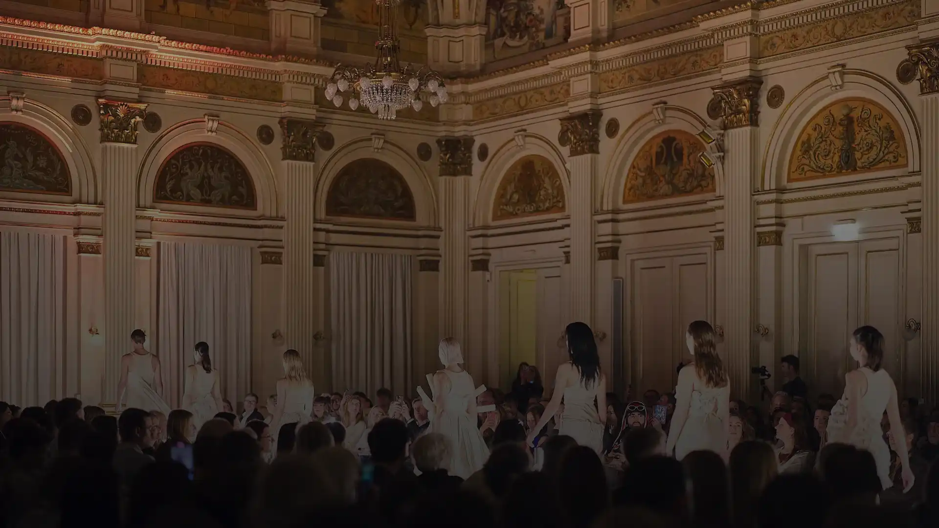 Zuschauer beobachten die Modenschau in einem festlichen Saal.