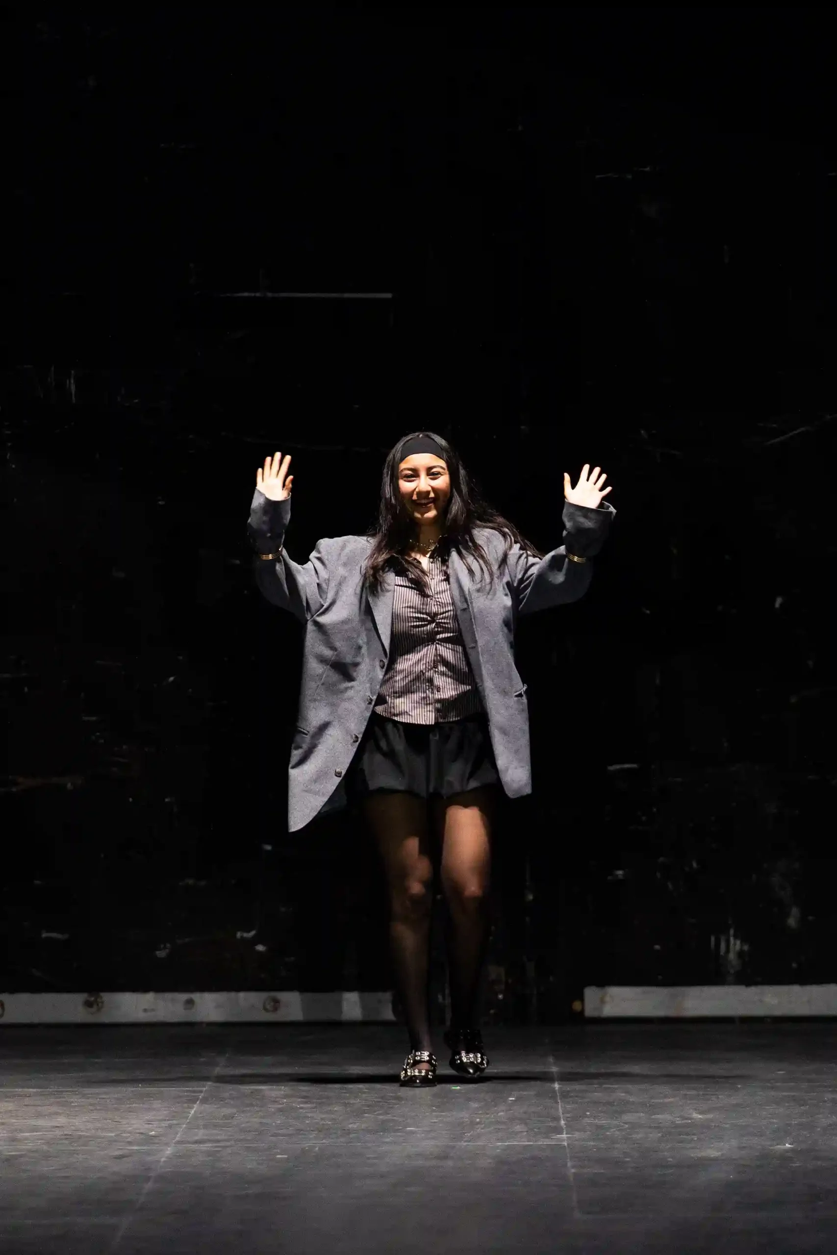 Eine Designerin in einem Blazer und Rock, die auf der Bühne posiert.