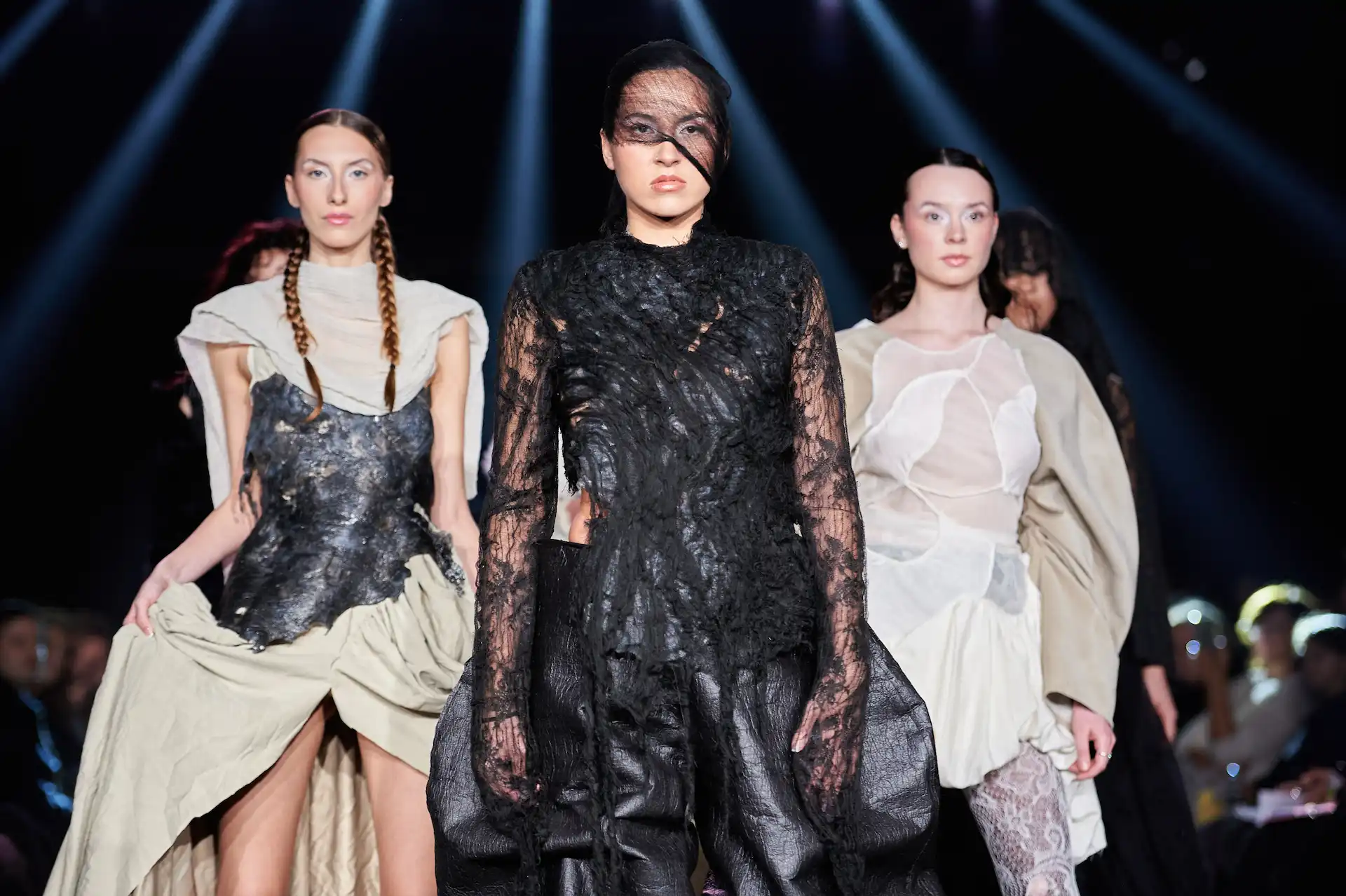 Sechs Models laufen über den Laufsteg und zeigen avantgardistische Schwarz-Weiß-Kleider, teilweise mit Spitze.