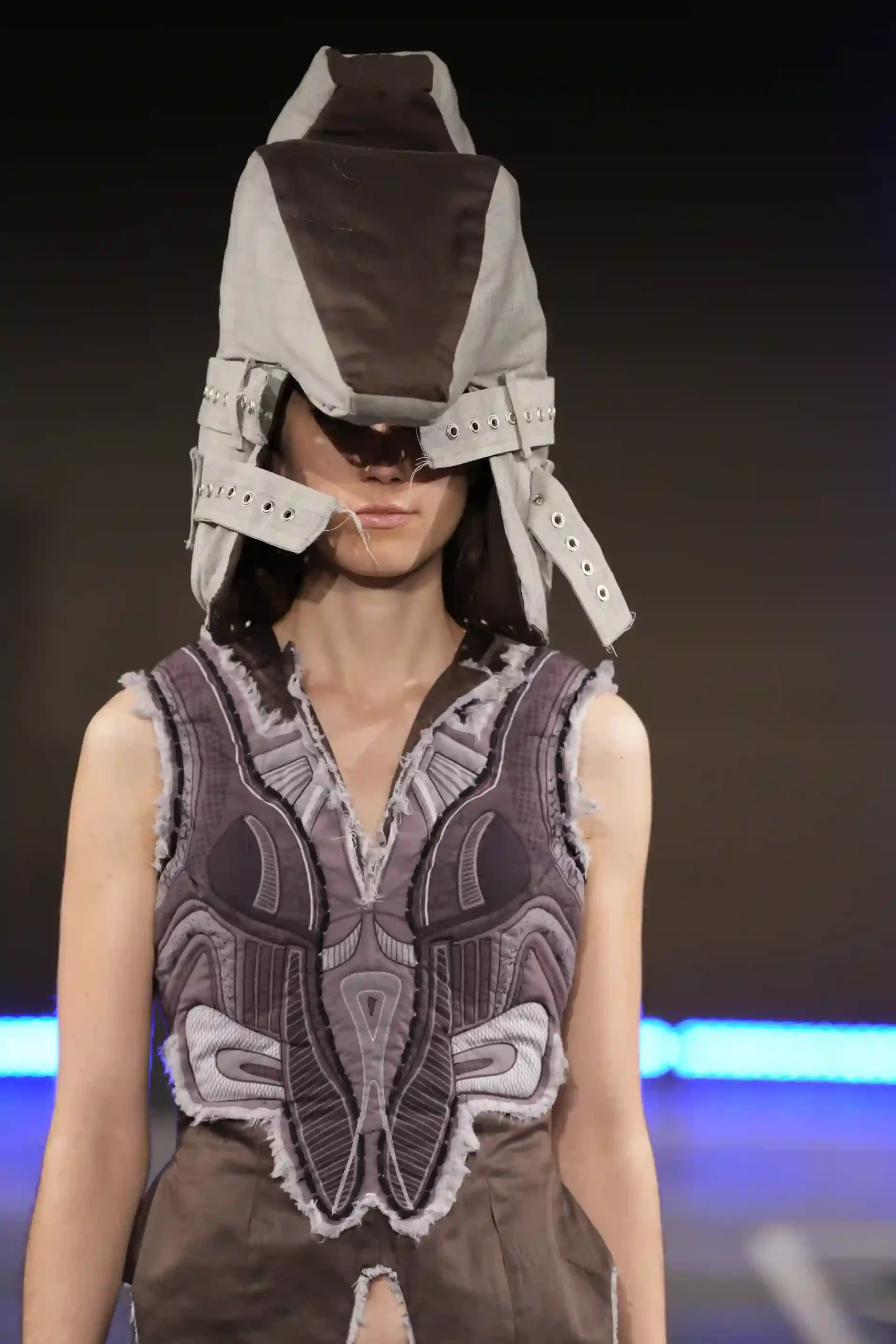 Model trägt futuristische Mode mit einem einzigartigen Hut.