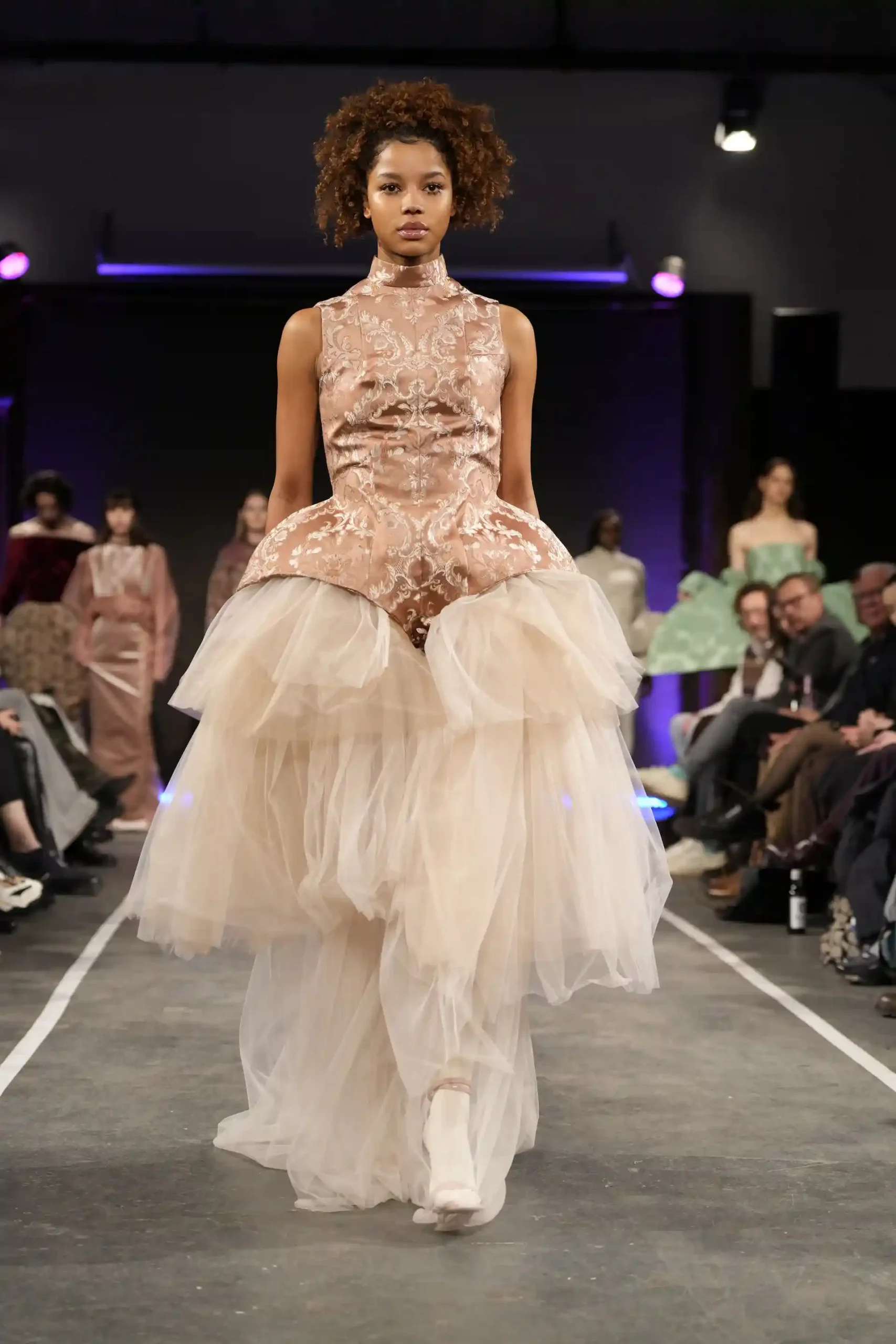 Model in eleganter Hochzeitskleidung mit Tüllrock auf dem Laufsteg.