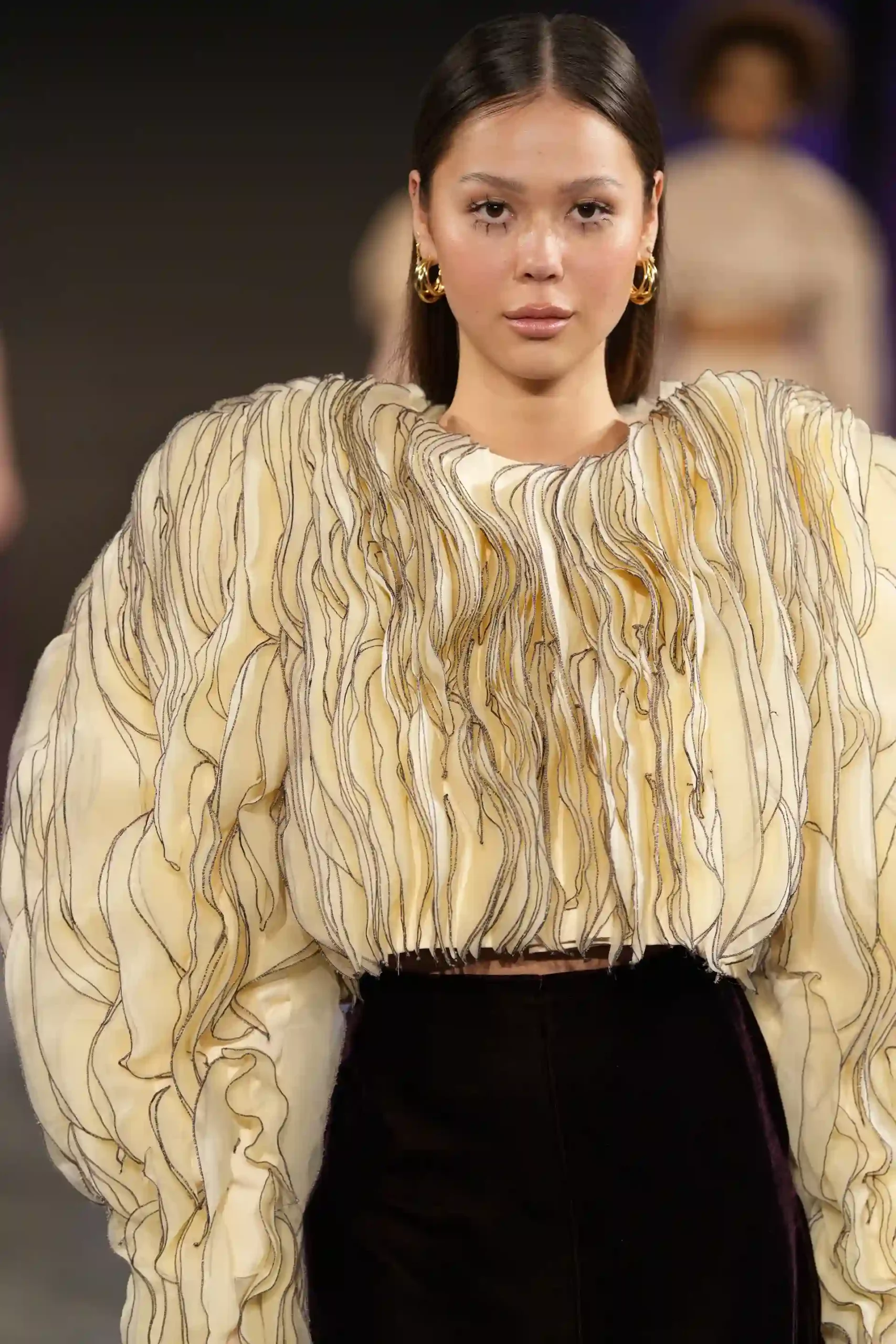 Model in einer eleganten Bluse mit Fransen und schwarzem Rock