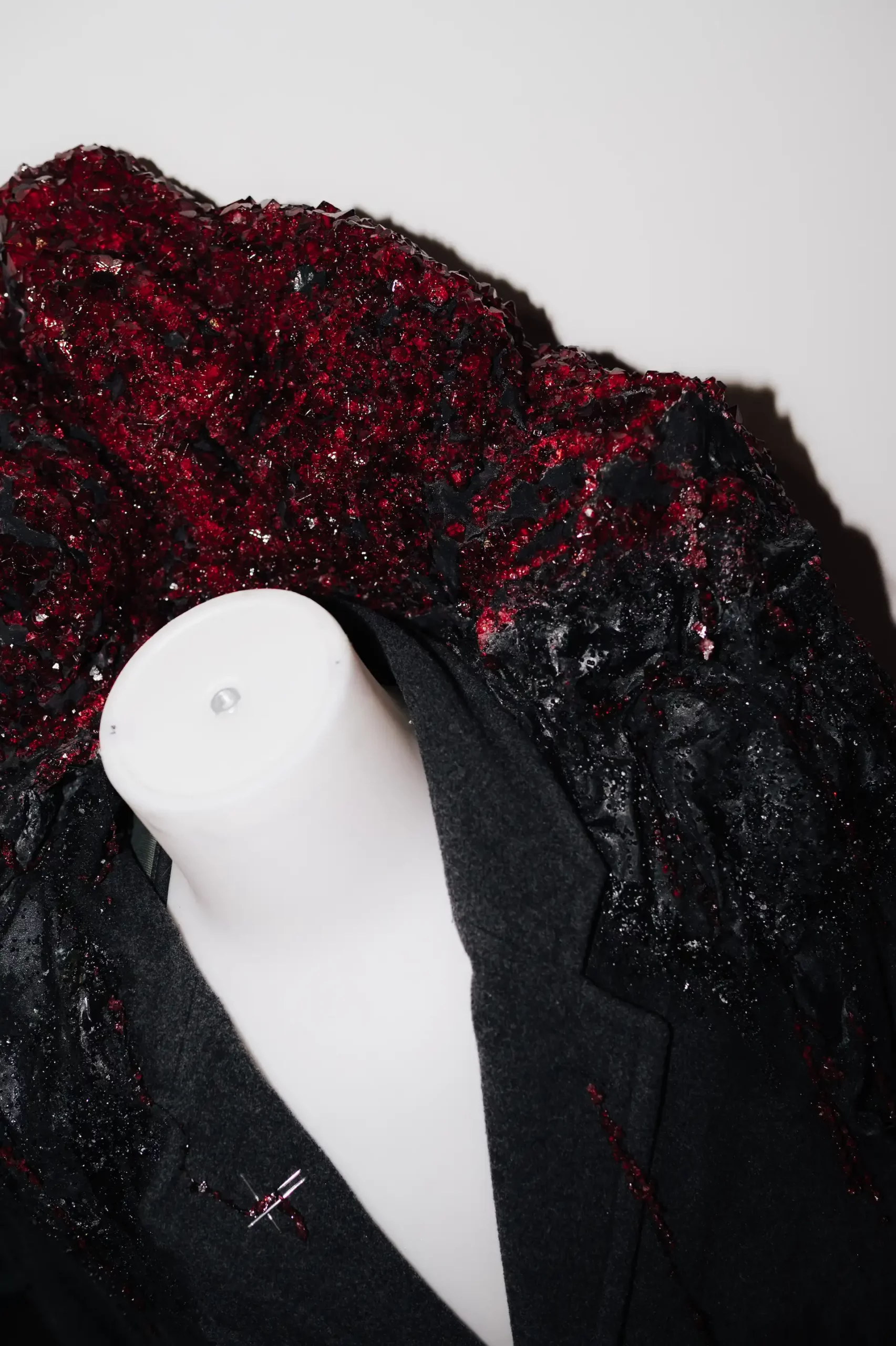 Kreatives Design eines Blazers mit auffälligen roten und schwarzen Edelsteinen.