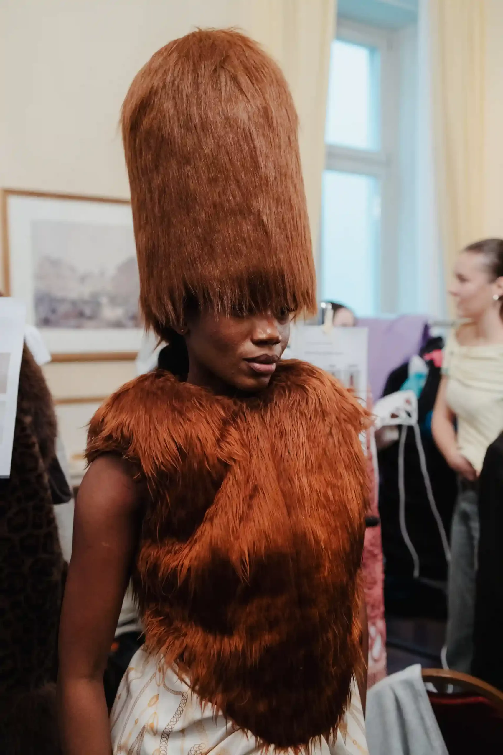 Backstage-Blick auf ein avantgardistisches Mode-Outfit mit einzigartigem Haarstyling.