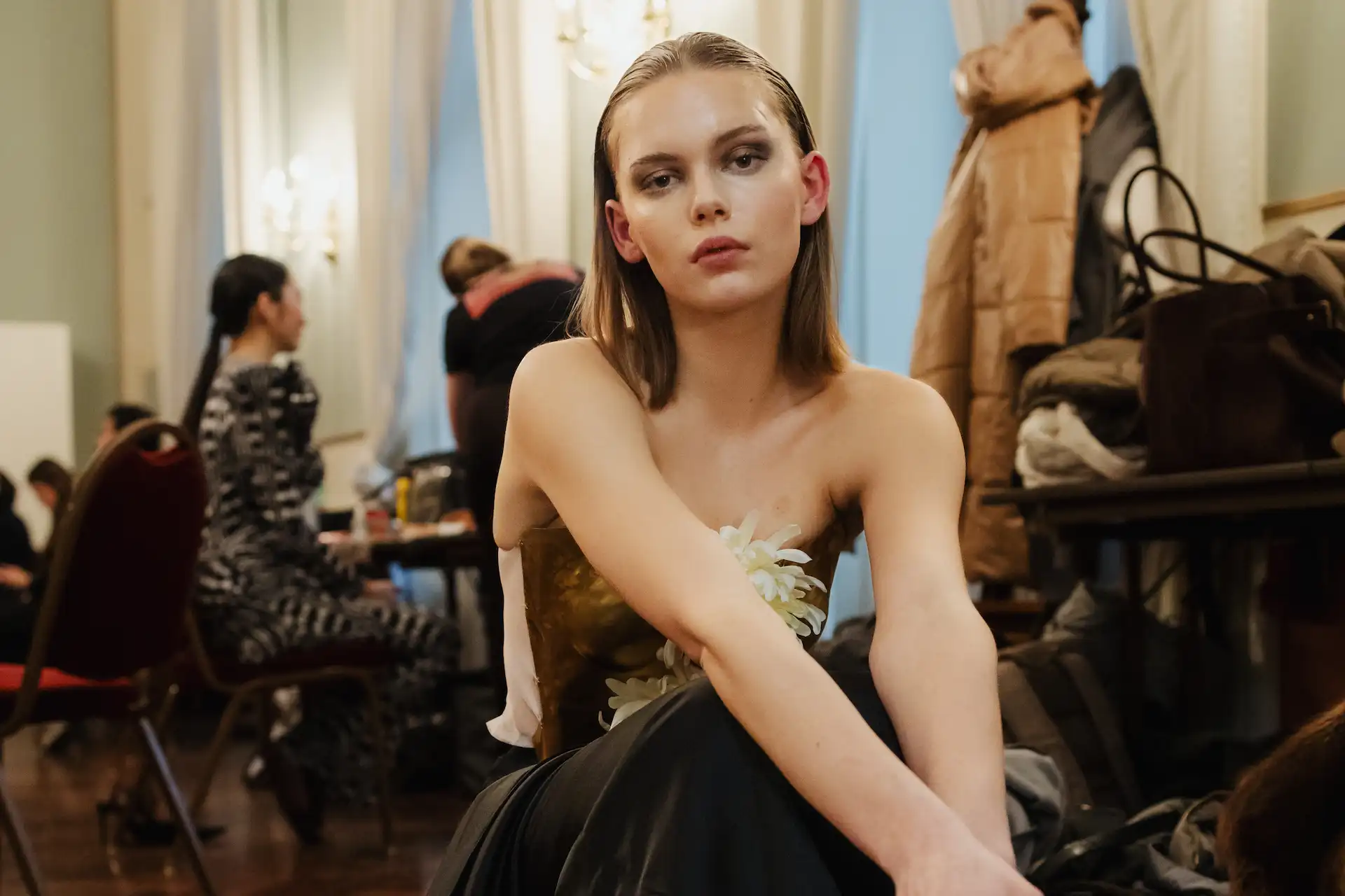 Ein bereits geschminktes Model sitzt hinter den Kulissen der Stage-Modenschau und wartet auf seinen Einsatz.