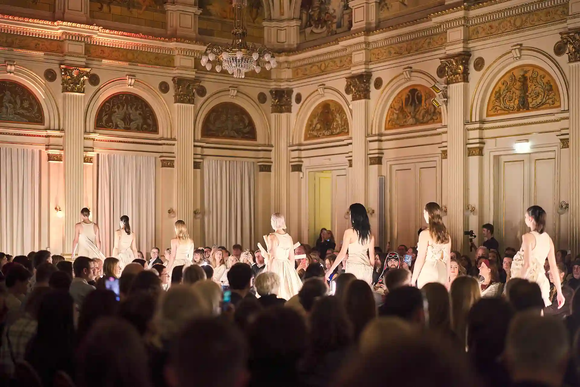 Zuschauer genießen die AMD-Stage- Modenschau in einem opulenten Saal.