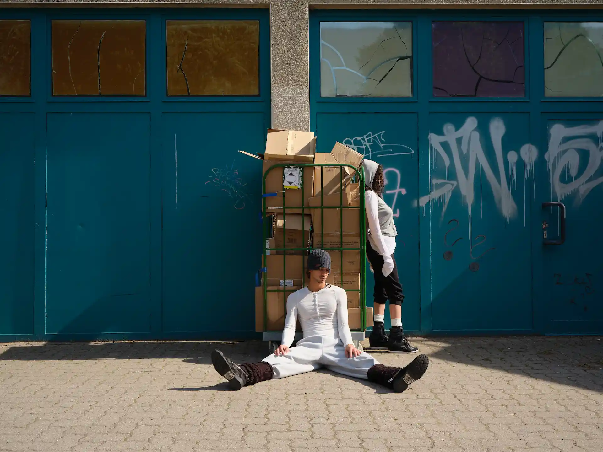 Person in gelbem Oberteil sitzt vor blauer Wand – Streetstyle-Aufnahme